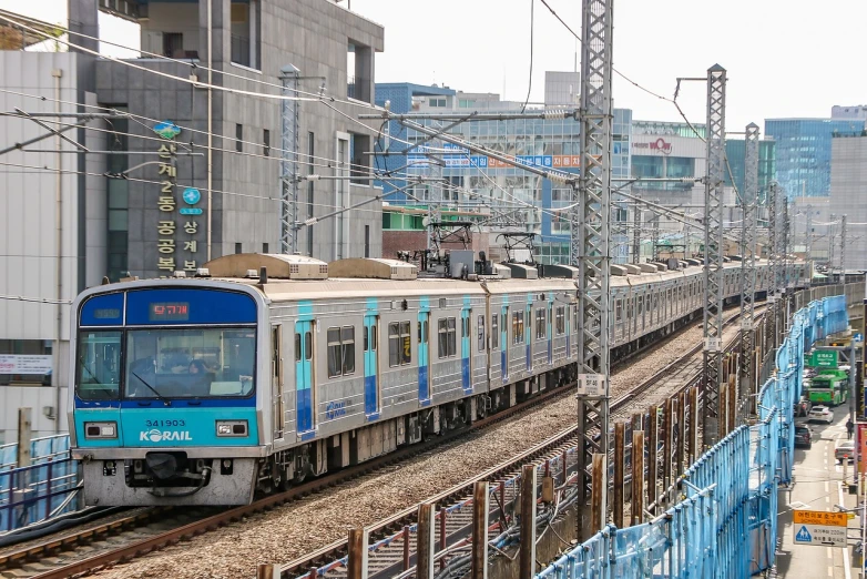 a large long train on a steel track, shutterstock, shin hanga, traditional korean city, blue and cyan scheme, in busy city, news photo