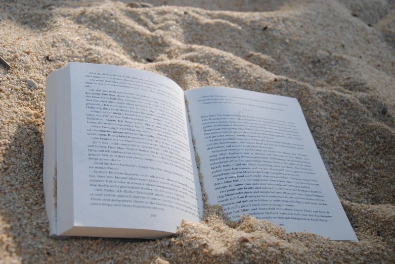 an open book sitting on top of a sandy beach, a portrait, by Romain brook, pexels, realism, bottom angle, turnaround, white, wallpaper - 1 0 2 4