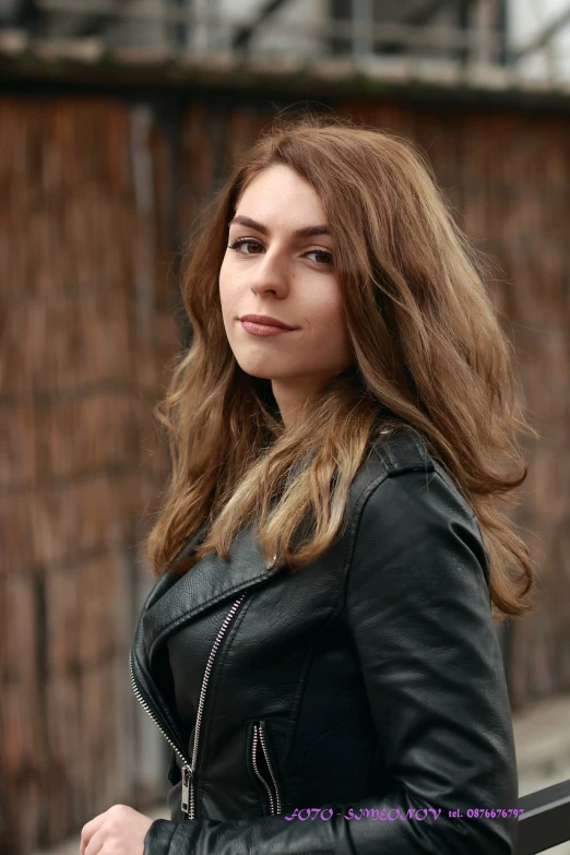 a woman in a leather jacket posing for a picture, a portrait, by Emma Andijewska, shutterstock, brown wavy hair, elegant girl in urban outfit, high detail portrait photo, aged 2 5