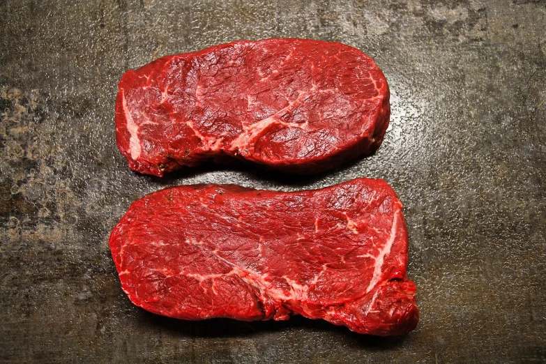 a couple of steaks sitting on top of a table, a stock photo, by Julian Hatton, meat texture, egypt, wisconsin, reddish