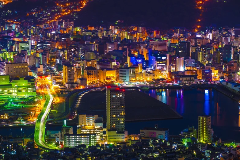 an aerial view of a city at night, by Naondo Nakamura, pexels contest winner, fine art, nagasaki, 4 k vertical wallpaper, a colorful, side