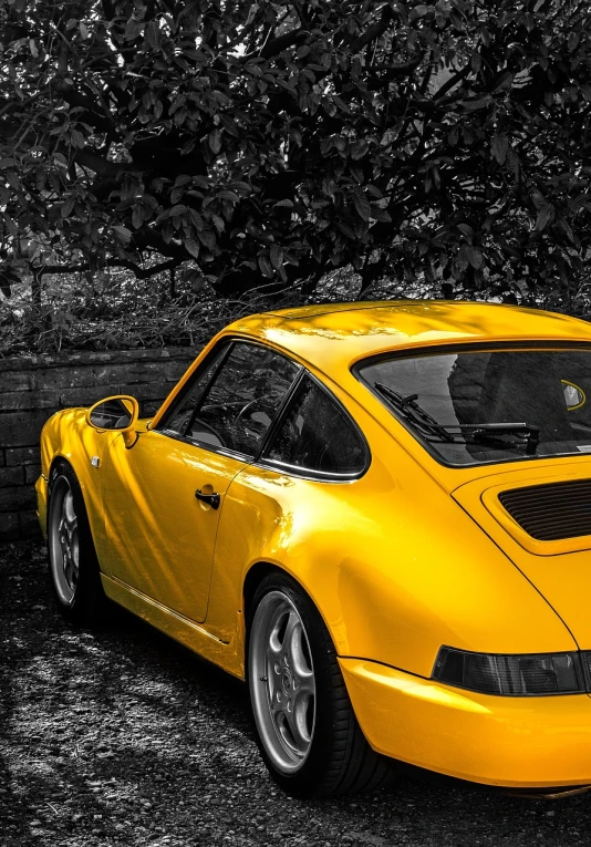 a yellow sports car parked next to a brick wall, a photo, inspired by Eric Dinyer, trending on pixabay, photorealism, porsche rsr, selective color effect, rear-shot, gold paint