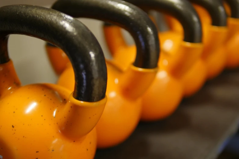 a row of kettlebells lined up on a table, by Adam Manyoki, flickr, black and orange colour palette, closeup of arms, piping, high res