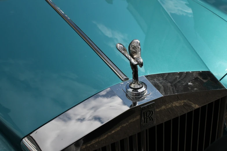 a close up of a car's hood ornament, a picture, by Roger Cecil, arabesque, aquamarine, wraith, 1/1250s at f/2.8, royality