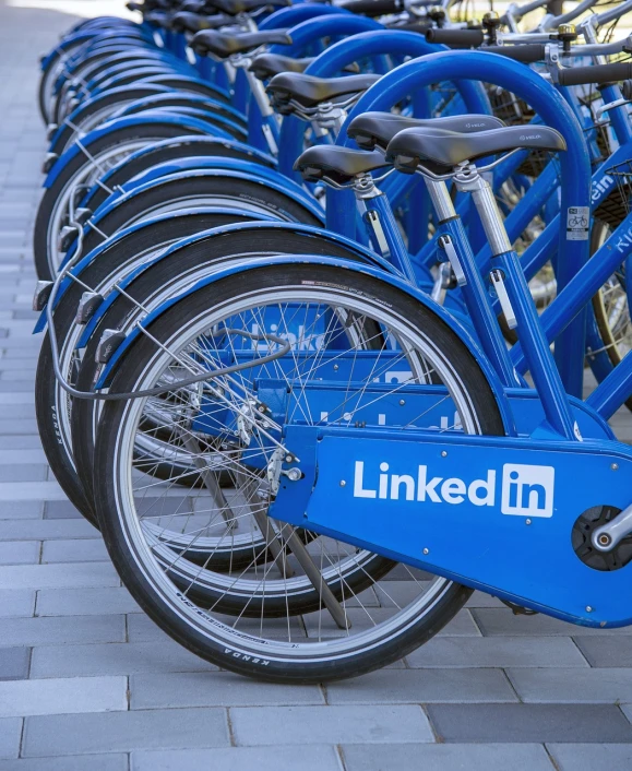 a row of blue linked bikes parked next to each other, a colorized photo, shutterstock, incoherents, linkedin, immersed within a network, engraved, ad image