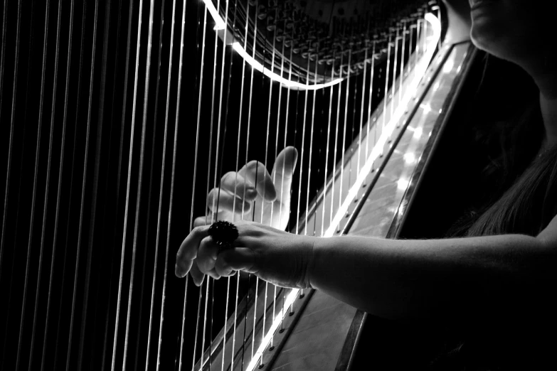 a black and white photo of a woman playing a harp, by Eugeniusz Zak, flickr, wires and strings, hand photography, strings background, soft glow