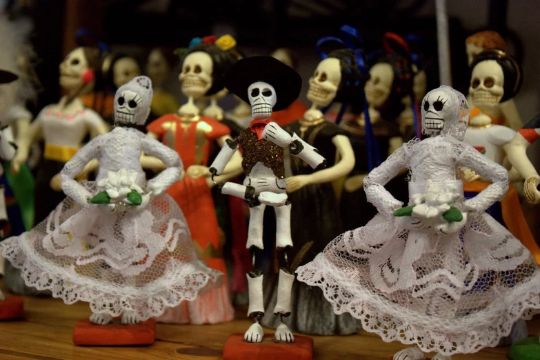 a group of skeleton figurines sitting on top of a wooden table, flickr, folk art, danza azteca dancers, bride, standing in a cantina, avatar image