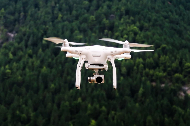 a white drone flying over a forest filled with trees, uhd photography, profile close-up view, discovered photo, instrument