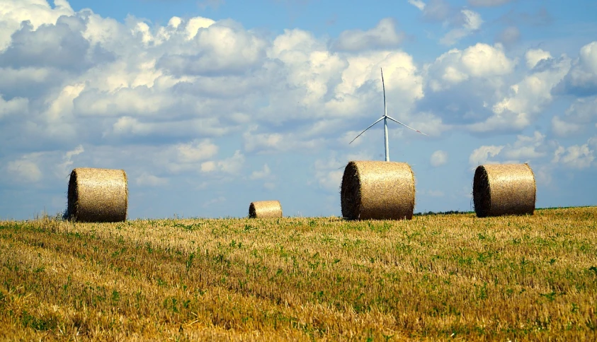 hay bales in a field with a wind turbine in the background, a stock photo, pixabay, istock, photo taken from far away, illinois, reportage photo