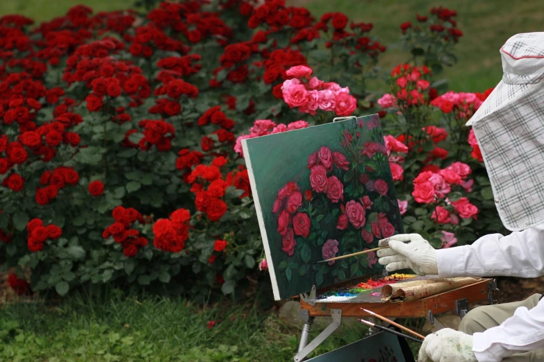 a person painting a picture in a field of flowers, a photorealistic painting, by Aleksandr Gerasimov, plein air, rose garden, afp, photograph credit: ap, decorative roses