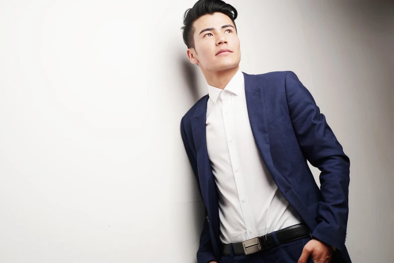 a man in a suit leaning against a wall, inspired by David Diao, attractive young man, looking upwards, frontal pose, in style of thawan duchanee