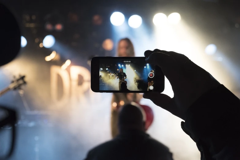 a person taking a picture of a concert with a cell phone, a picture, by Christen Dalsgaard, happening, performing a music video, dlsr photo, live broadcast, sd video