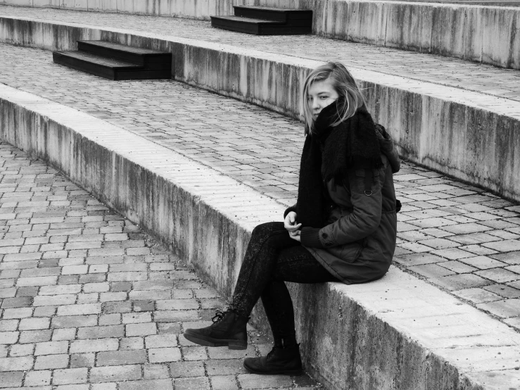 a black and white photo of a woman sitting on steps, a black and white photo, by Anna Boch, tumblr, cold weather, 🤤 girl portrait, marthe jonkers, urban surroundings