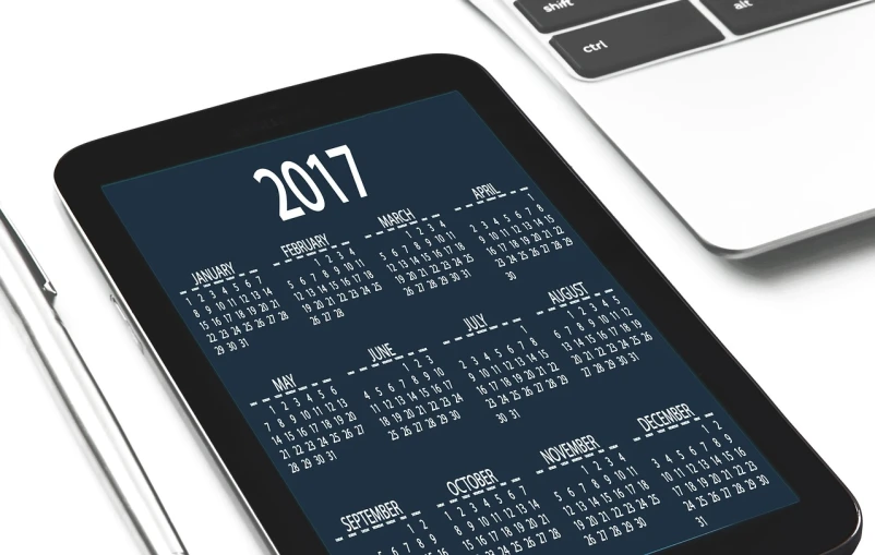 a tablet computer sitting on top of a desk next to a laptop computer, by Andrei Kolkoutine, pixabay, happening, female calendar, new years eve, pristine and clean design, captured on iphone