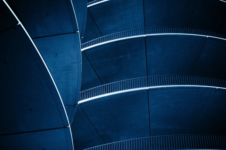 a black and white photo of a curved building, a photo, by Matthias Weischer, unsplash contest winner, abstract design. blue, external staircases, dark blue tones, overpass