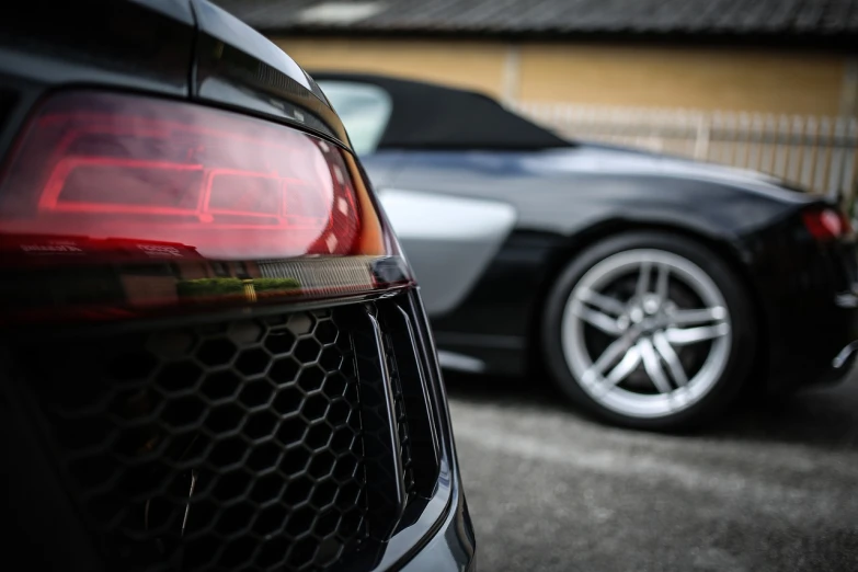 two cars parked next to each other in a parking lot, a picture, by Thomas Häfner, exquisite and smooth detail, f1.8 bokeh, close-up shot taken from behind, dragon in the background