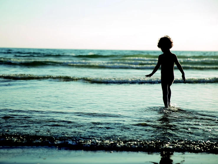 a little boy that is standing in the water, a picture, minimalism, istockphoto, girl on the beach, silhouetted, detailed surroundings