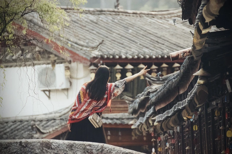 a woman standing on top of a roof next to a building, inspired by Miao Fu, happening, travel, pointing, old asian village, beautiful aesthetic