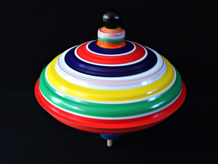 a colorful spinning toy on a black surface, inspired by Jan Rustem, flickr, bauhaus, pagoda, ufo, very large, striped