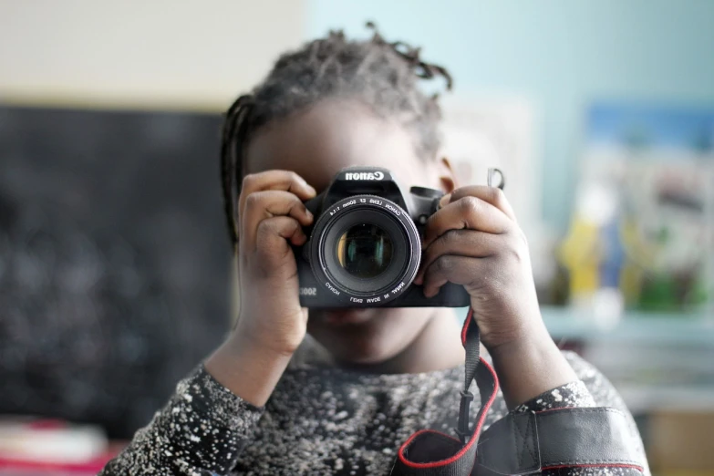 a little girl taking a picture with a camera, inspired by Gordon Parks, unsplash, light skinned african young girl, dslr camera img_4016, closed up portrait, home photography portrait