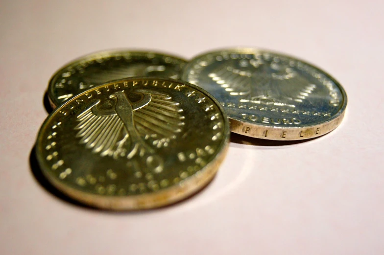 a couple of coins sitting on top of each other, by Konrad Klapheck, flickr, gold foil, eagle, detailed product photo, rays