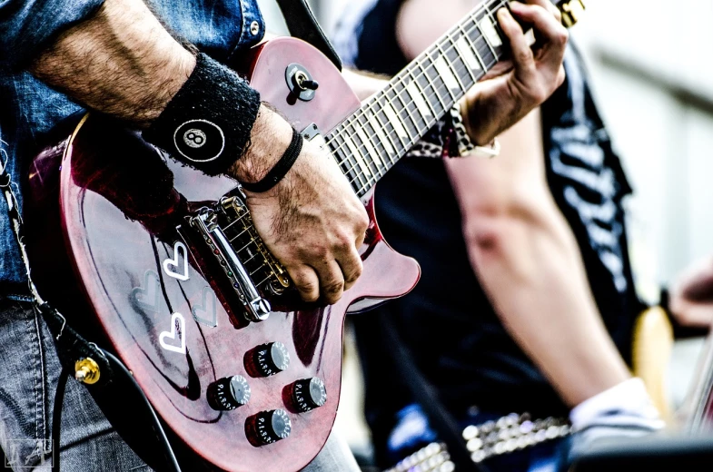 a close up of a person playing a guitar, by Alexander Fedosav, pixabay, heavy metal concert, action sports photography, ((oversaturated)), holding electric guitars
