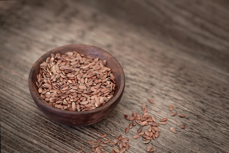 a wooden bowl filled with flax seeds on top of a wooden table, a portrait, by Yun Du-seo, pexels, renaissance, smooth red skin, readhead, 🦩🪐🐞👩🏻🦳, paul barson