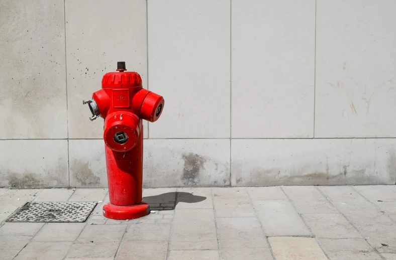 a red fire hydrant sitting on the side of a building, a photo, shutterstock, street art, nobody here, glass pipes showing red, four legged, trending on dezeen