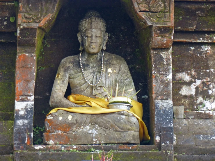 a statue of a person sitting in a niche, a statue, sumatraism, with yellow cloths, bowl, floating in a powerful zen state, clothed in ancient