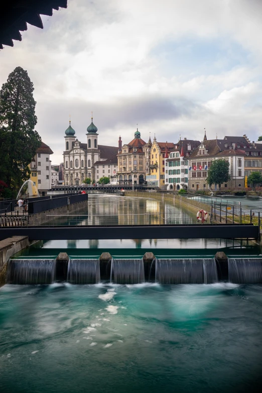 a river running through a city next to a bridge, by Karl Stauffer-Bern, shutterstock, water flowing through the sewer, long exposure photograph, stock photo, swiss architecture