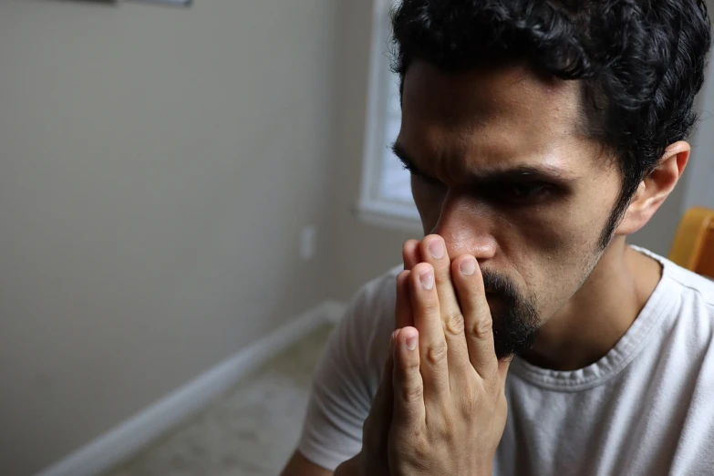 a man sitting at a table with his hands in front of his face, by Adam Rex, reddit, sweaty 4 k, bedroom eyes, looking from side!, praying posture