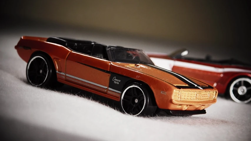 a couple of toy cars sitting next to each other, inspired by Otto Eckmann, unsplash, photorealism, lowriders, orange tint, sleek interceptor profile, hot wheels