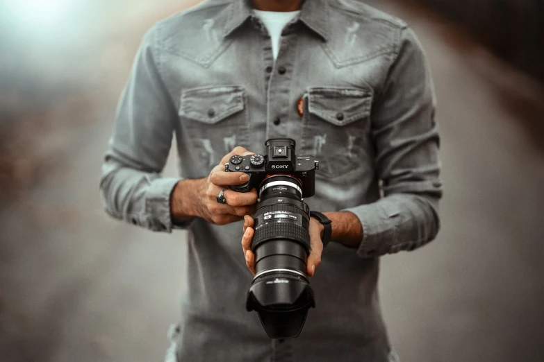 a man holding a camera in his hands, sony lens, promotional photography, action photograph, professional image