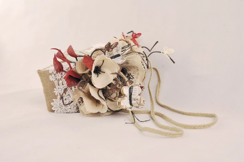 a close up of a purse on a white surface, by Maki Haku, art nouveau, wrapped in flowers and wired, burlap, headpiece headpiece headpiece, side-view