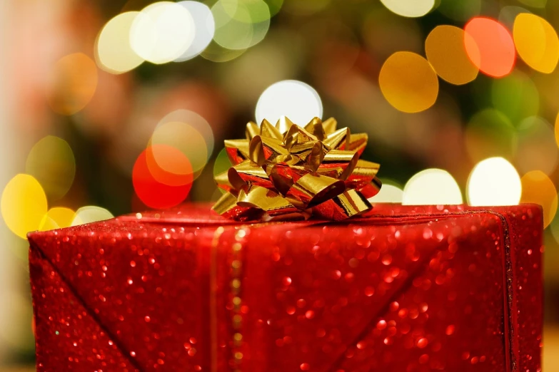 a red gift box sitting on top of a table, by January Suchodolski, happening, golden glistening, a close-up, wrapped, awesome