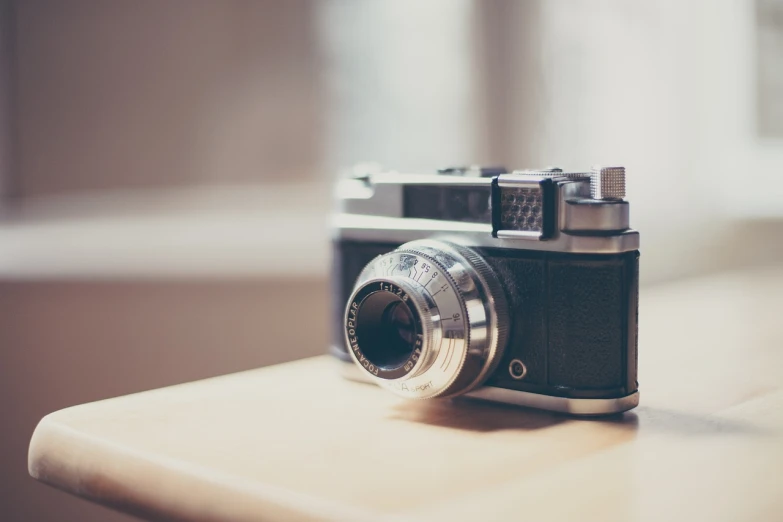 a camera sitting on top of a wooden table, a picture, unsplash, vintage soft grainy, posing for the camera, low camera, bokeh. chrome accents