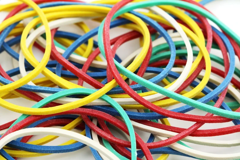 a pile of multicolored rubber bracelets on a white surface, plasticien, floggers, highly detailed product photo