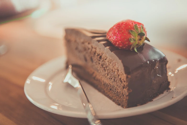 a piece of chocolate cake with a strawberry on top, a picture, by Karl Buesgen, pexels, retro effect, high delicate defined details, caramel, cafe