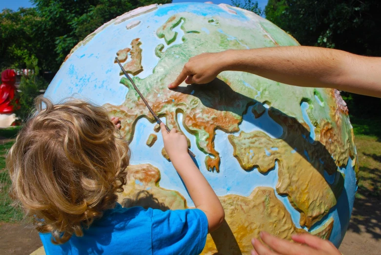 a little boy standing next to a giant globe, a photo, by Erwin Bowien, shutterstock, sculpting, detailed zoom photo, teaching, sundial