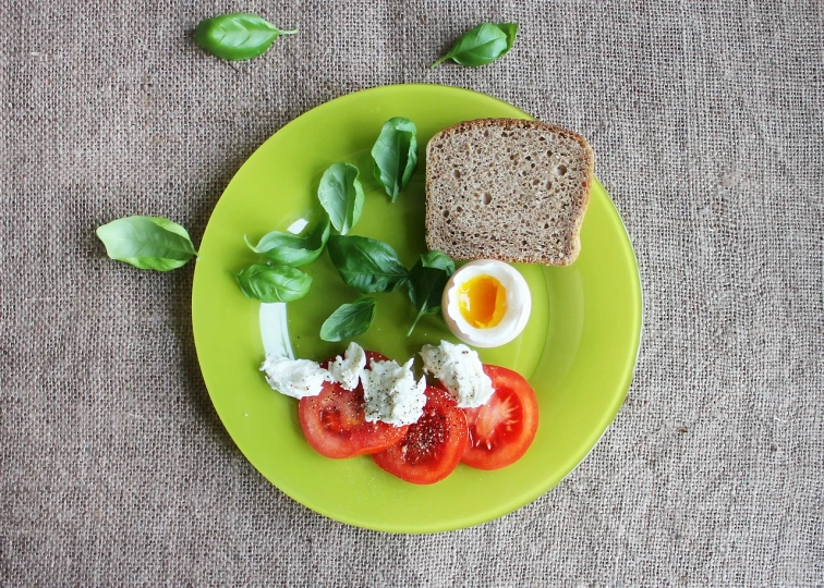 a close up of a plate of food on a table, by Anna Haifisch, pixabay, minimalism, red and green color scheme, egg, sandwich, basil gogos