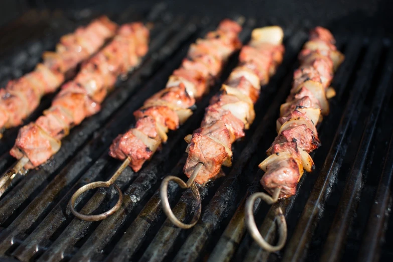 a close up of skewered meat on a grill, by Matt Cavotta, shutterstock, hurufiyya, avatar image, straps, orthodox, 33mm photo