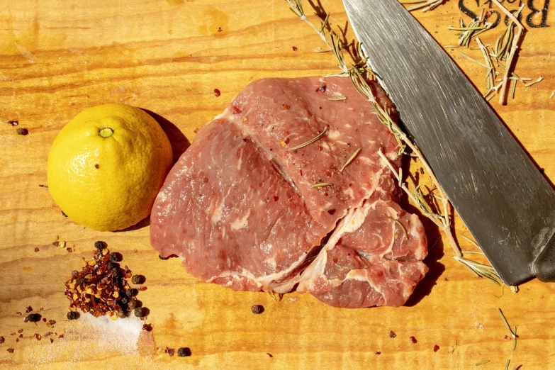 a piece of meat sitting on top of a cutting board next to a lemon, renaissance, on a sunny day, round chin, southern slav features, dramatic product shot