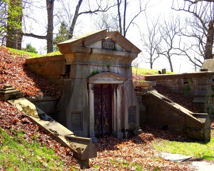 a small stone building sitting on top of a lush green hillside, a photo, by Robert Lee Eskridge, renaissance, inside a tomb, olmsted, many doorways, dead