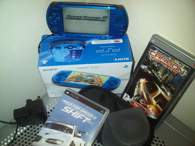 a nintendo game system sitting on top of a table, a photo, psp, need for speed, blue fire!, inside its box