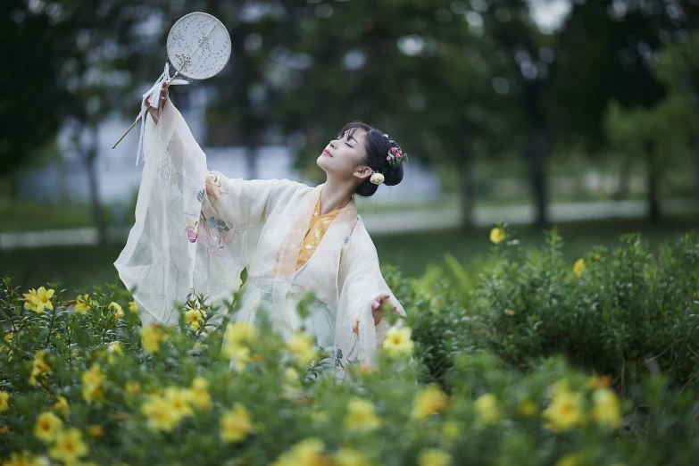 a woman holding a fan in a field of flowers, a picture, by Wen Zhenheng, art photography, hanfu, shot on 85mm, she is dancing, pan ren wei