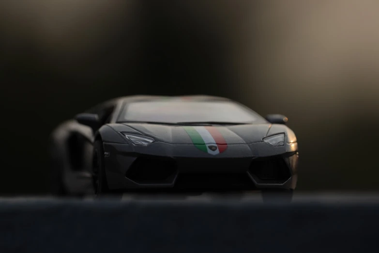 a toy car sitting on top of a table, a tilt shift photo, inspired by Bernardo Cavallino, pexels contest winner, photorealism, lamborghini, italian flag, background ( dark _ smokiness ), front of car angle