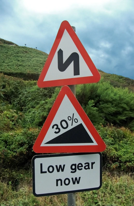 a couple of signs sitting on the side of a road, by John Wilson, flickr, ((gears)), steep cliffs, rule of third!!!!, !! low contrast!!