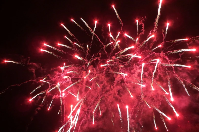 a large fireworks is lit up in the night sky, atmospheric red lighting, striking colour, red and white lighting, red led lights