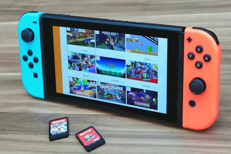 a nintendo switch lite sitting on top of a wooden table, a picture, by Tom Wänerstrand, maximalism, roblox, taken in the late 2010s, screens, playing