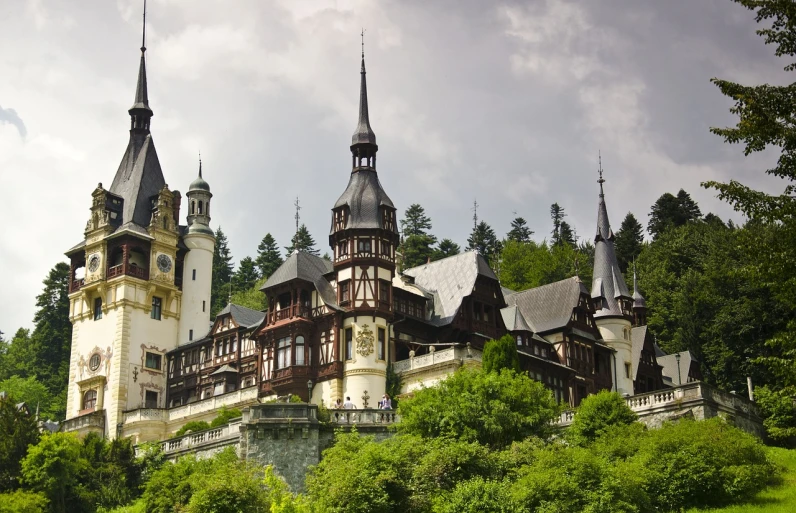 a castle sitting on top of a lush green hillside, art nouveau, romanian heritage, black domes and spires, ornate wood, white